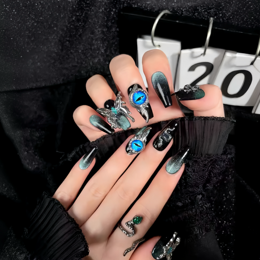Close-up of a hand with decorative nails and rings, wearing a black sleeve.