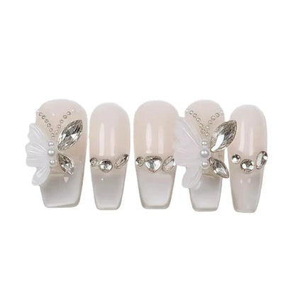 Set of decorative false nails with pearls and rhinestones on a white background