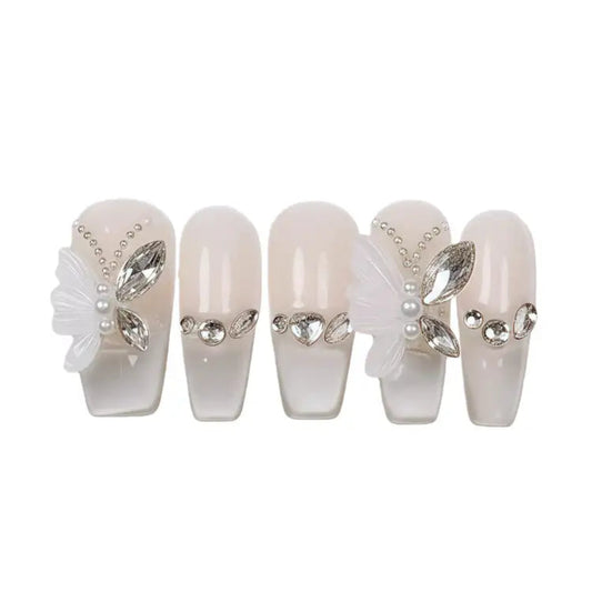 Set of decorative false nails with pearls and rhinestones on a white background