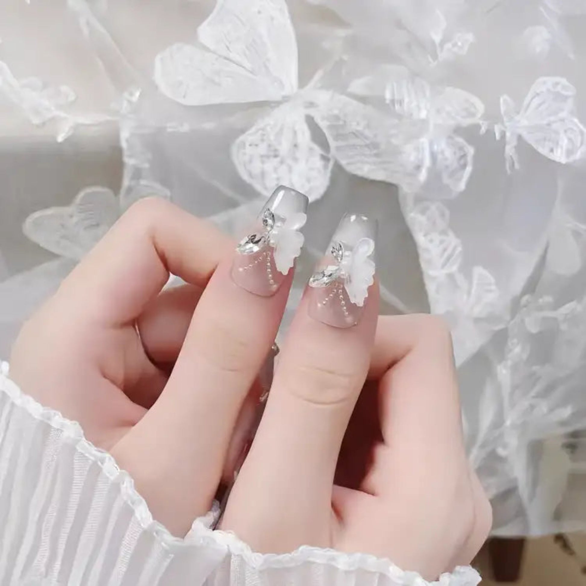 Hand with clear nail polish featuring floral designs against a soft, blurred background