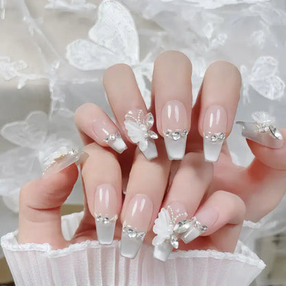 Nails with floral and crystal decorations held by a person wearing a white lace garment.