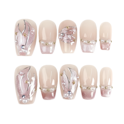 Set of decorative false nails with floral designs and pearls on a white background