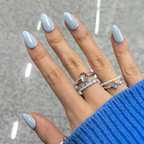 Hand with light blue nail polish and multiple rings on a gray background