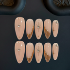 Set of decorative false nails with gold and silver designs on a dark background