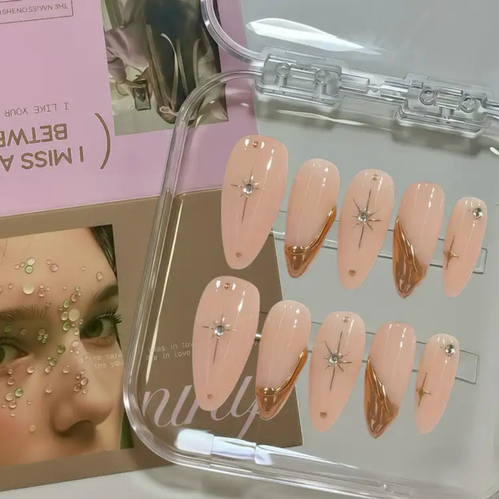 Set of pink and gold nail art designs in a clear case with a magazine in the background.