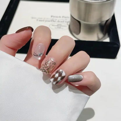 Hand with stylish nail art holding a silver cup on a white surface