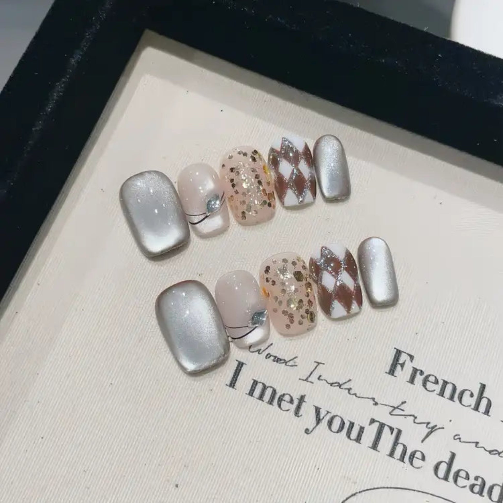 Set of decorative false nails on a textured surface with text.