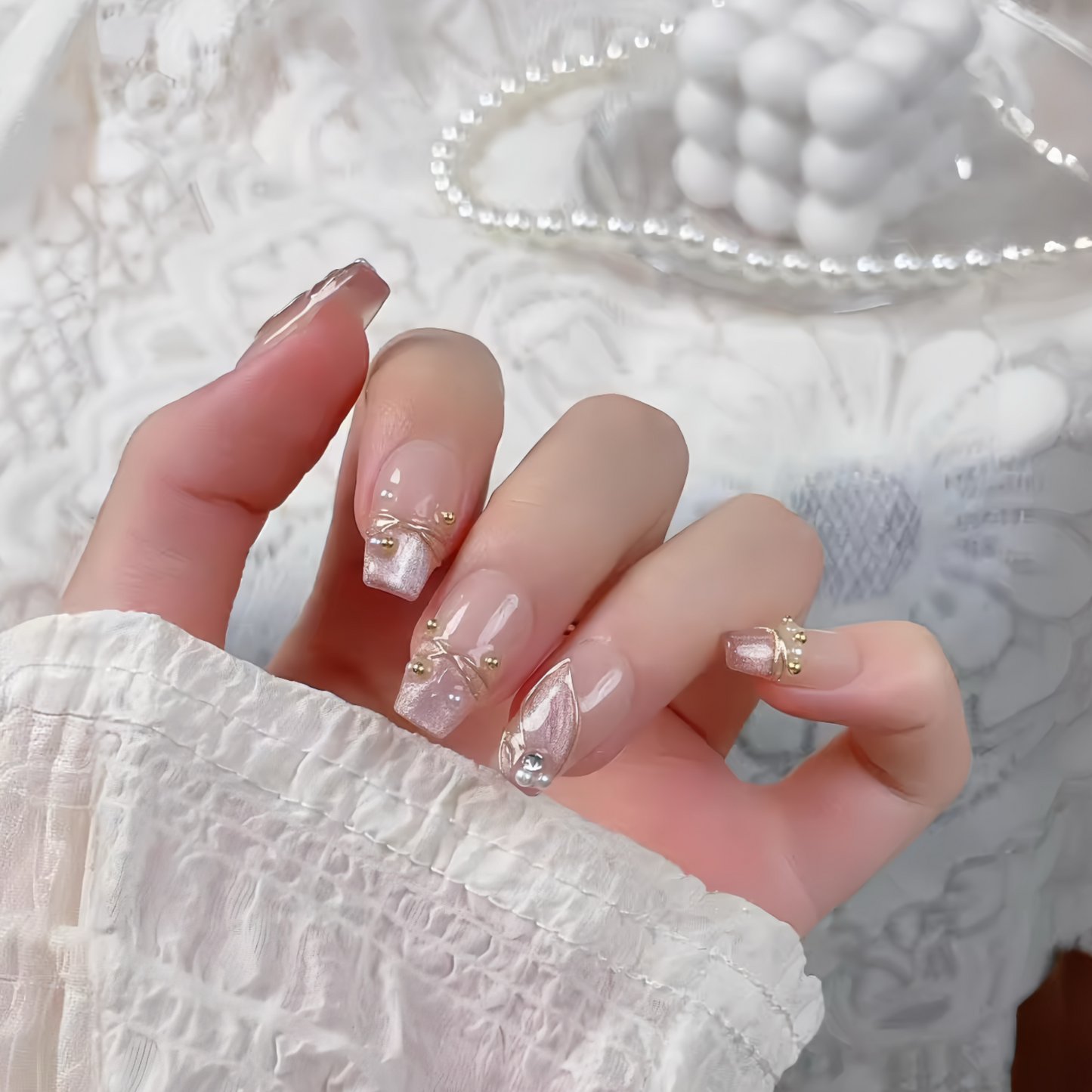 Hand with decorative nail art on a textured white background