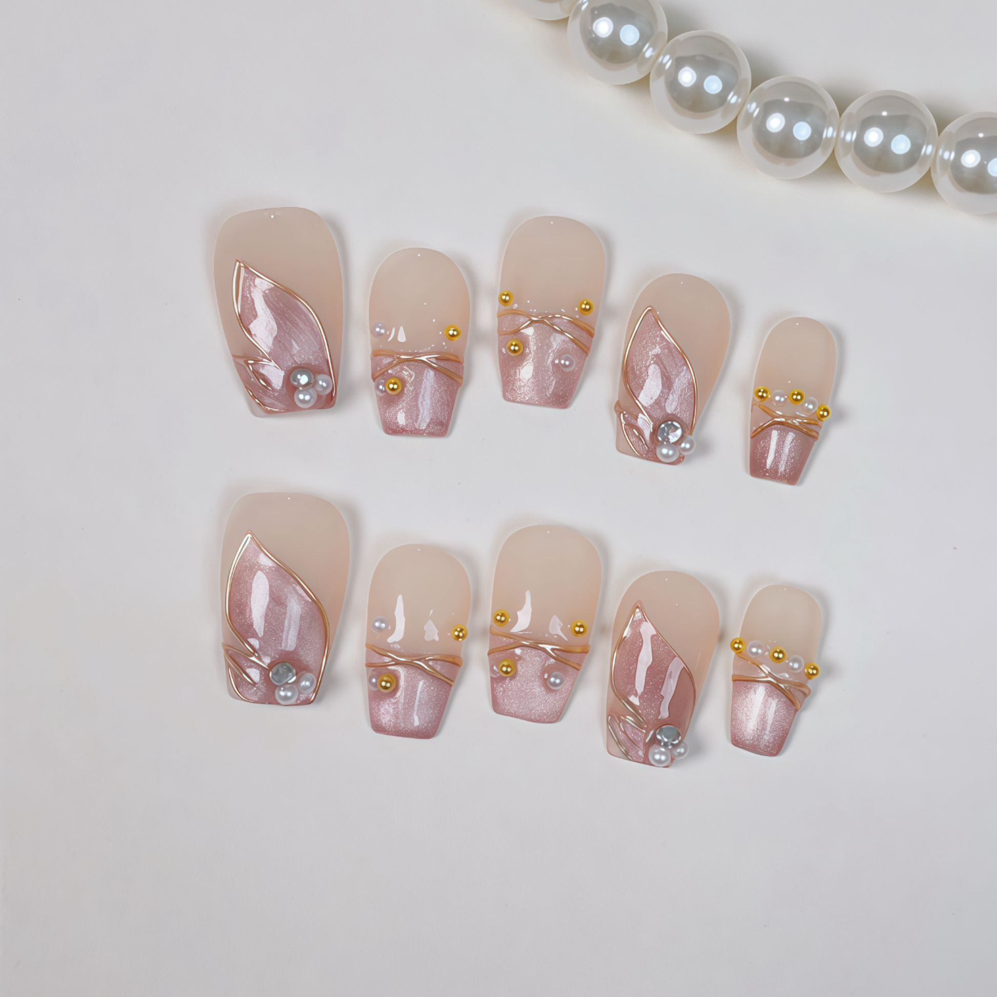 Set of decorative nails with a pearl and gold accent on a light background