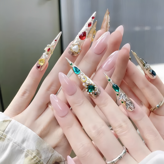 Close-up of hands with decorative nail art featuring gemstones and pearls.