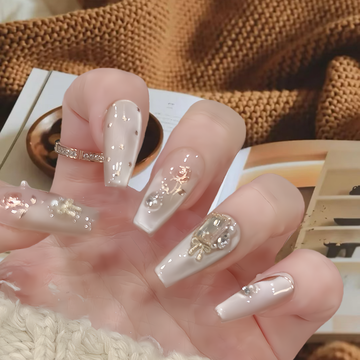 Hand with decorative nails holding a book, with a brown textured background