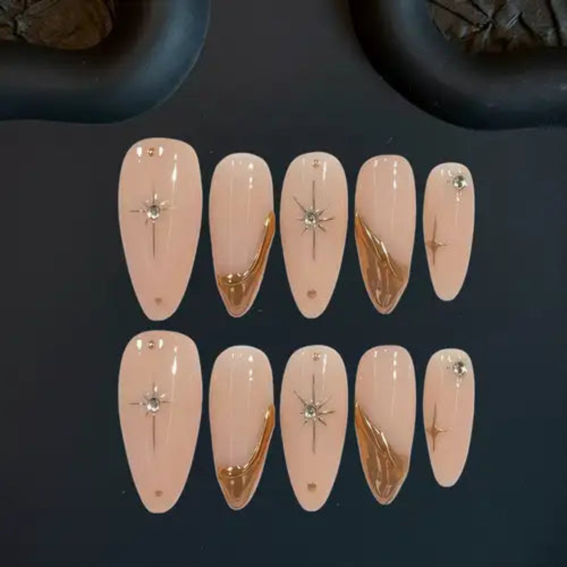 Set of decorative false nails with gold and silver designs on a dark background