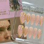 Set of pink nail art designs with gold accents in a clear case, with a magazine in the background.