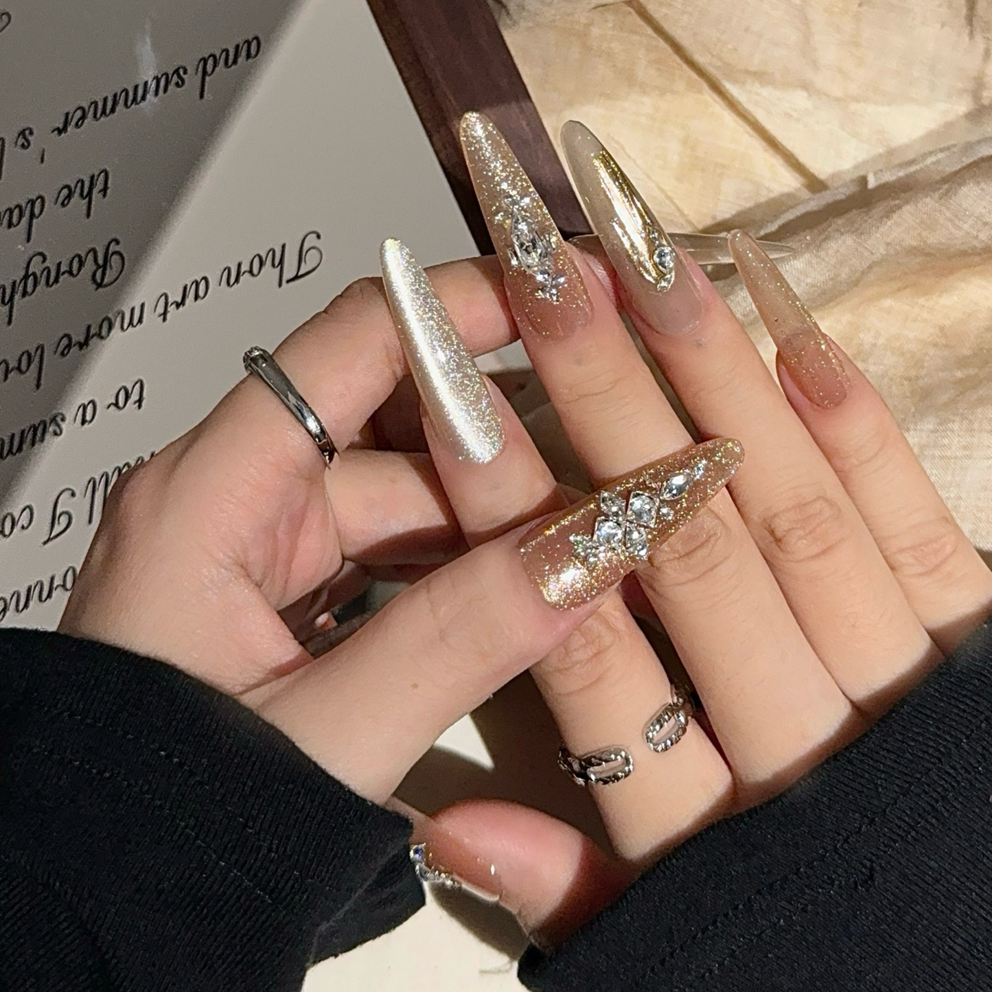 Hand with glittery nail art holding a book