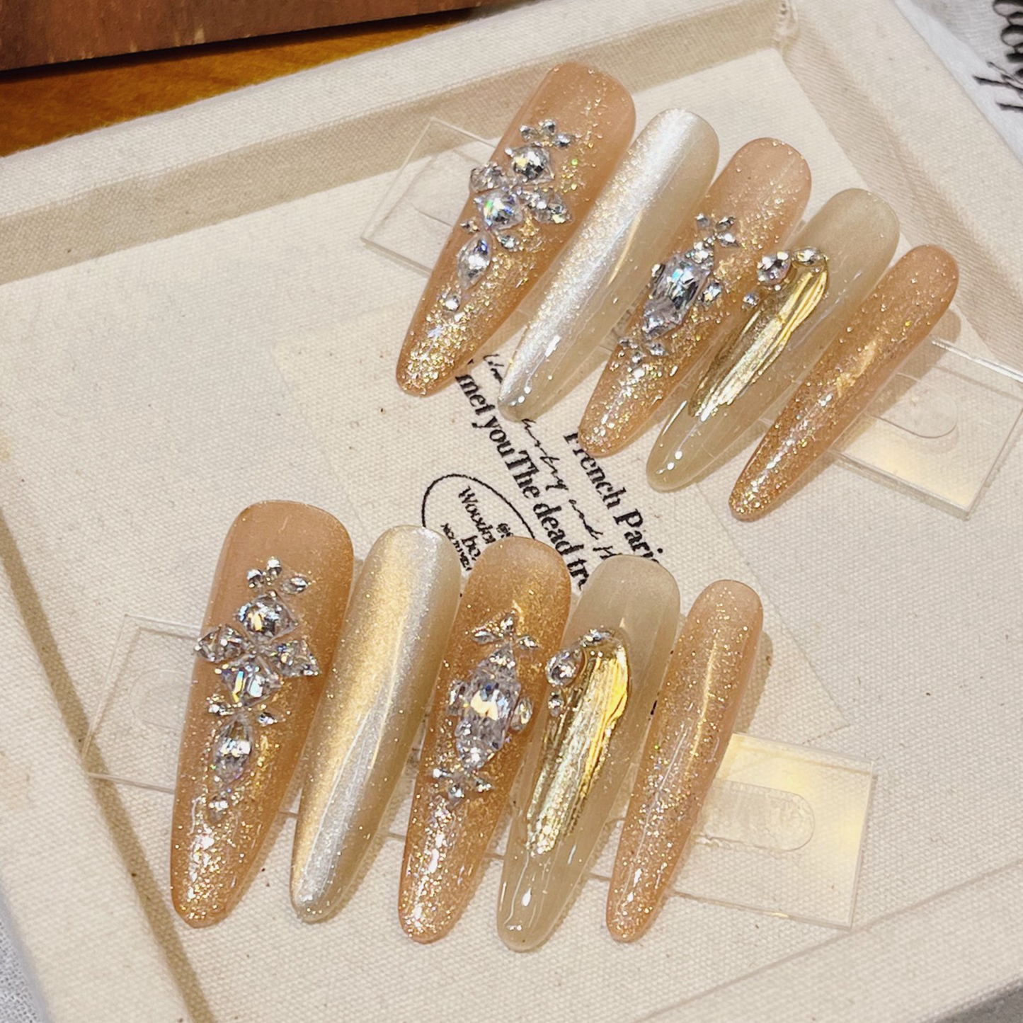 Decorative false nails with rhinestones on a textured surface