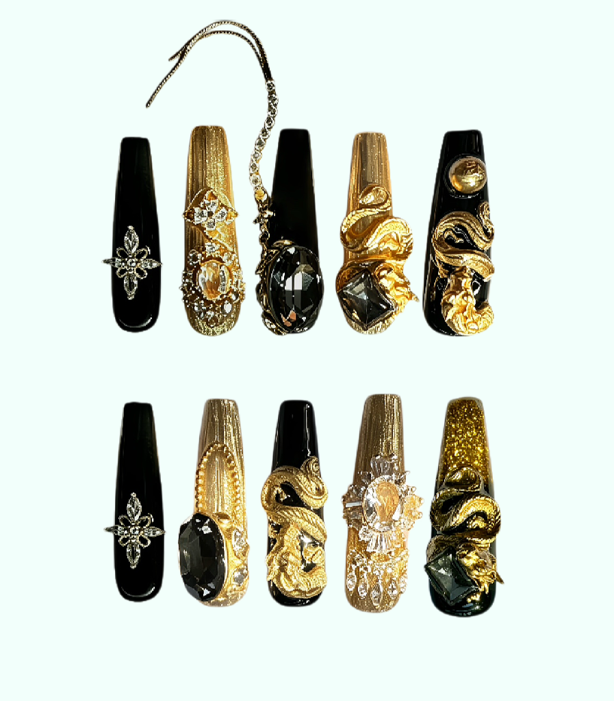 Decorative nail tips with gold and black designs on a white background