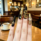 Decorative nail art with gold and black designs in a cafe setting
