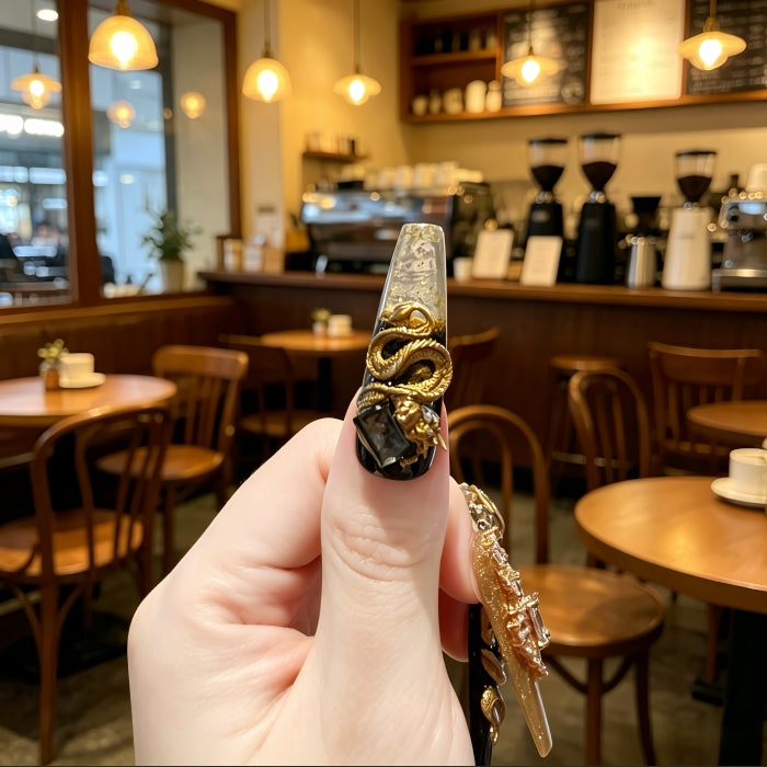 Gold and black ring with dragon design held in front of a cozy café interior.
