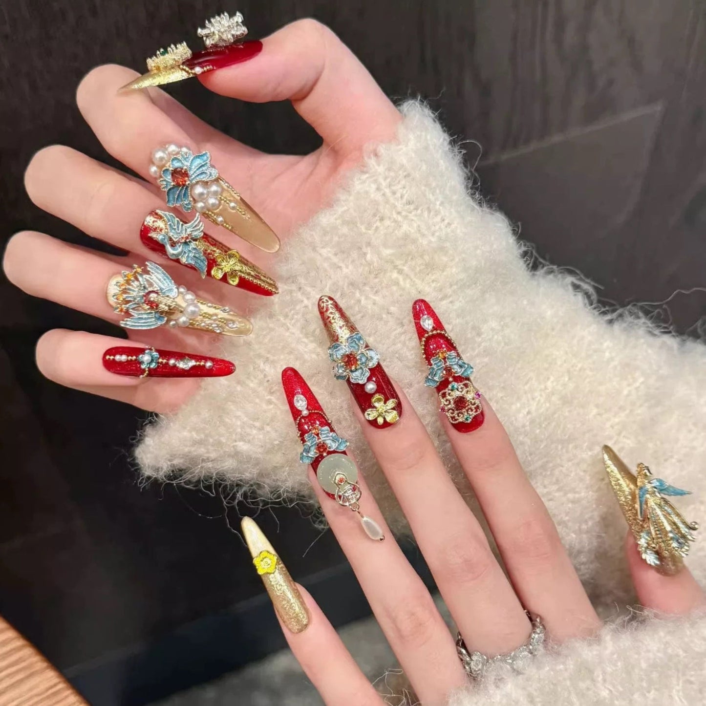 Hand with ornate nail art on a textured surface