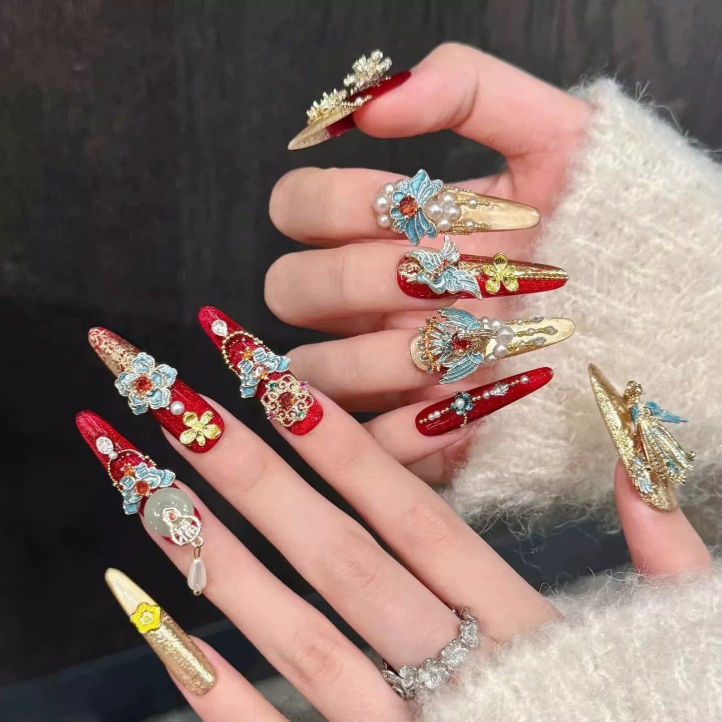 Decorative nail art with red, gold, and blue colors on a dark background