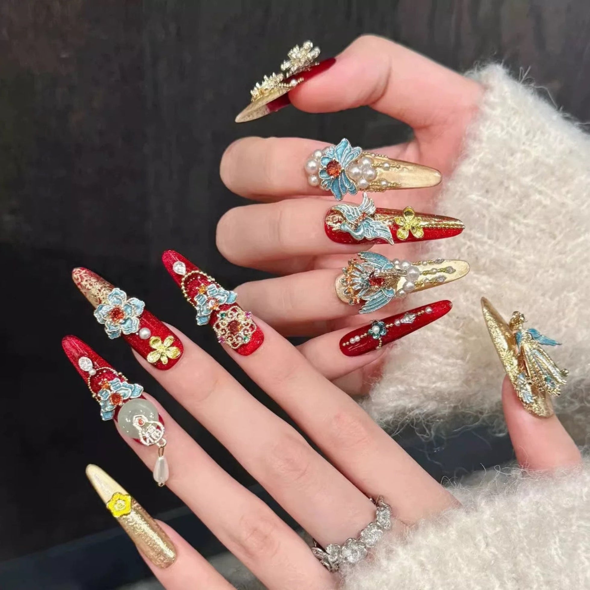 Decorative nail art with red, gold, and blue colors on a dark background