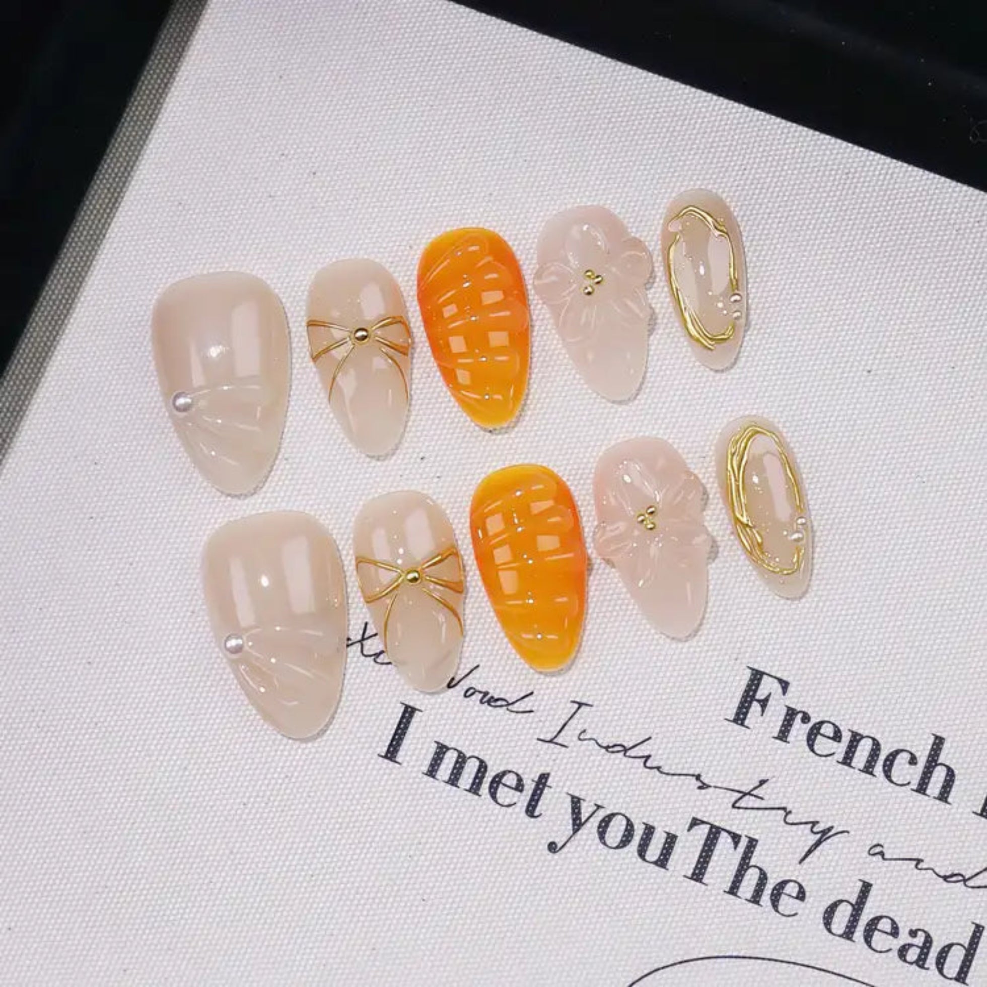 Set of decorative nail art pieces on a textured surface with text.