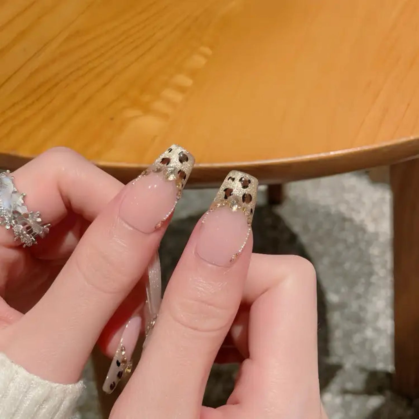 Close-up of hands with decorative nail art on a wooden surface