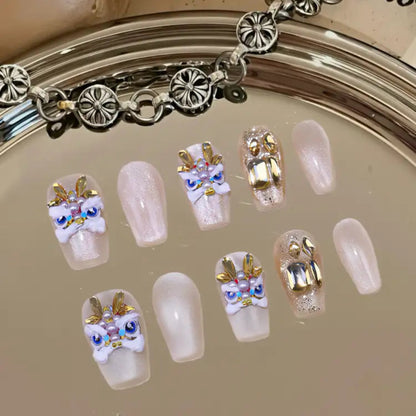 Decorative false nails with gold and white designs on a reflective surface.