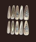 Set of decorative nails with gemstone and metallic designs on a dark background