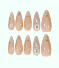 Set of pink false nails with gold accents and pearls on a white background