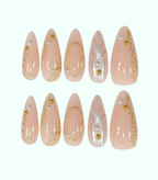 Set of pink false nails with gold accents and pearls on a white background