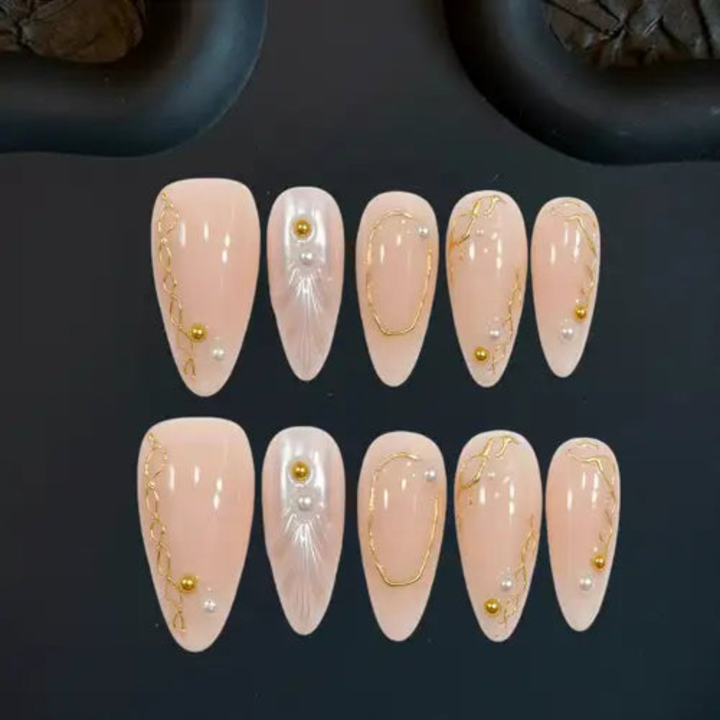 Set of pink nail art designs with gold accents on a dark background