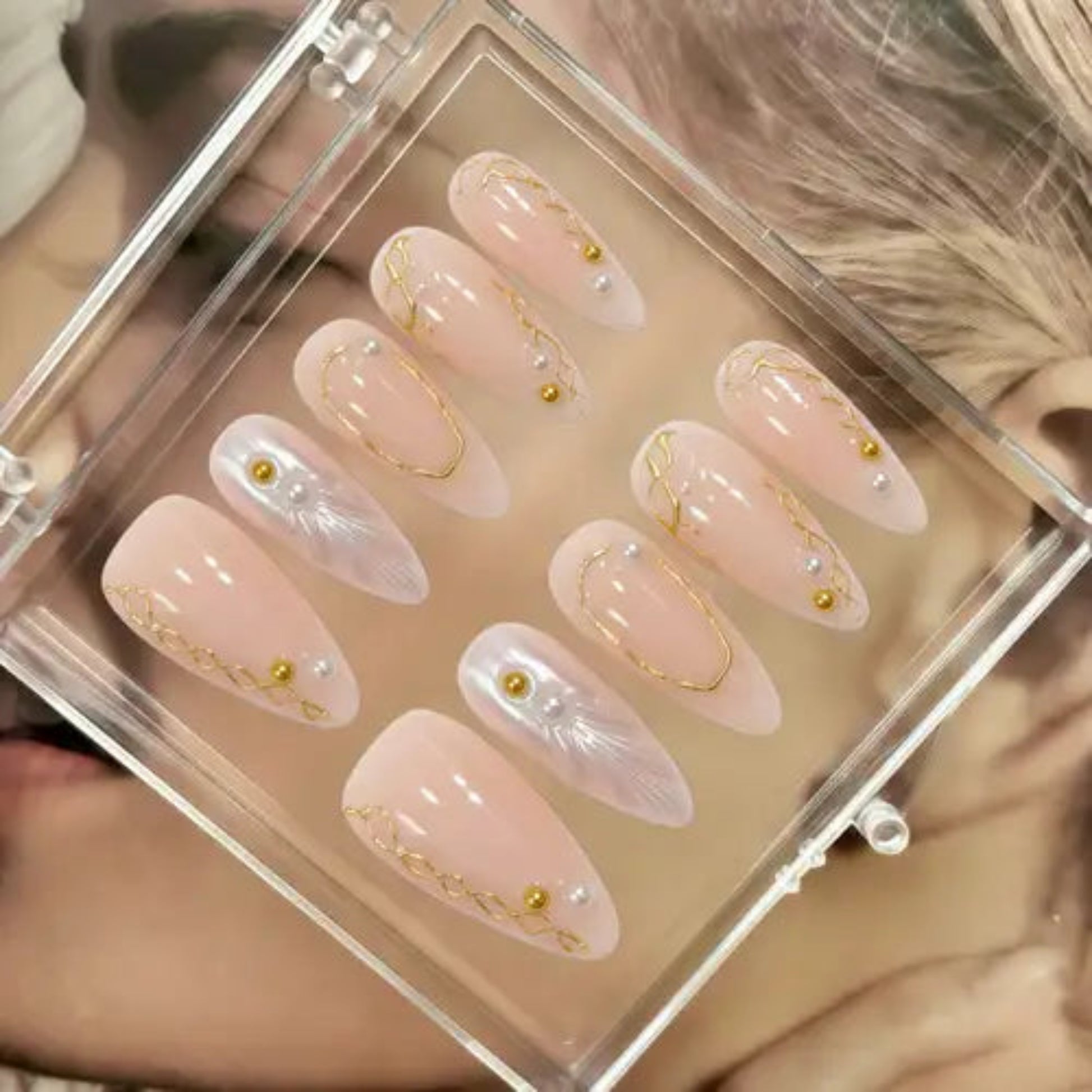 Set of decorative false nails with gold accents in a clear case.