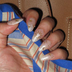 Close-up of a hand with decorative nail art on a patterned fabric background