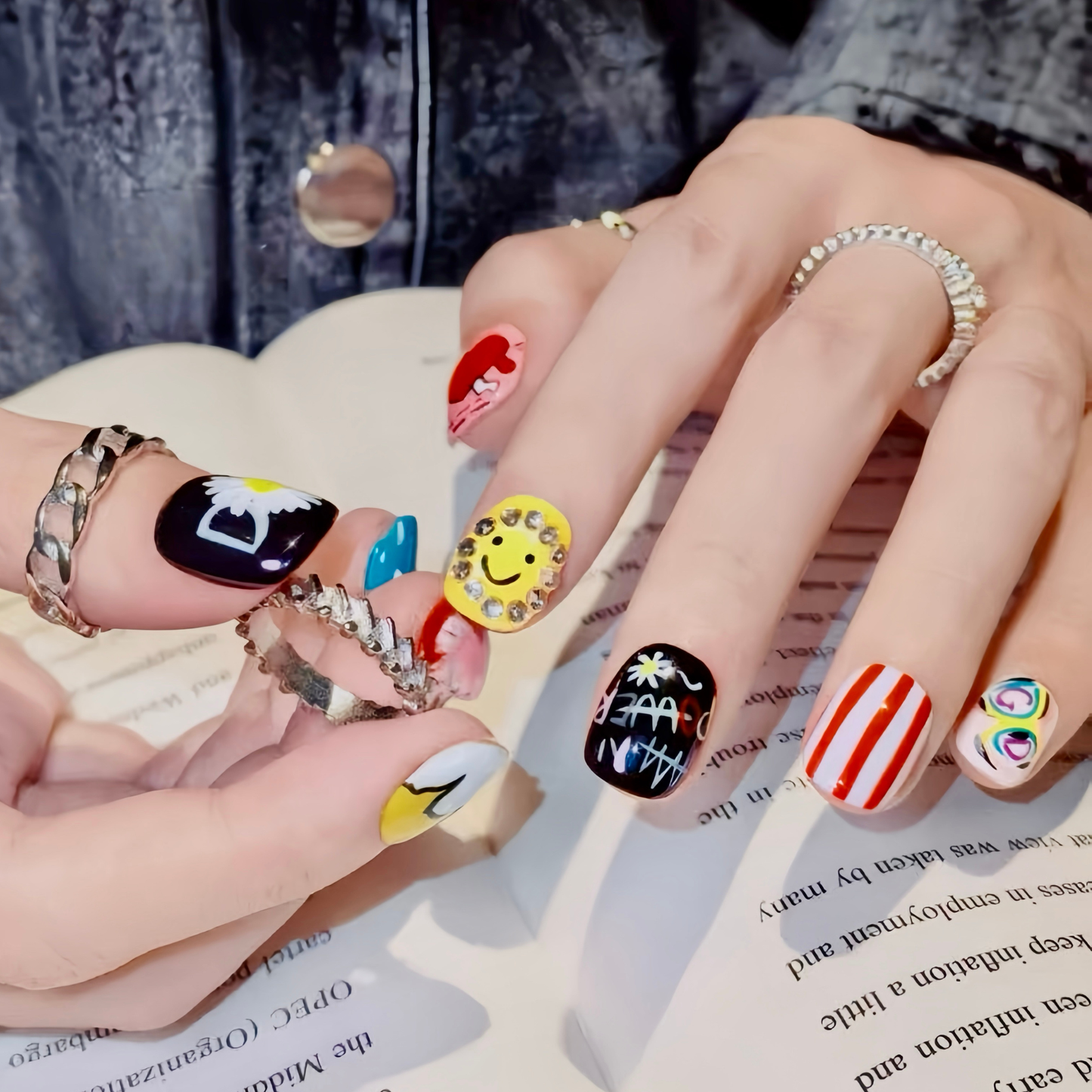 Close-up of hands with colorful nail art on a book background