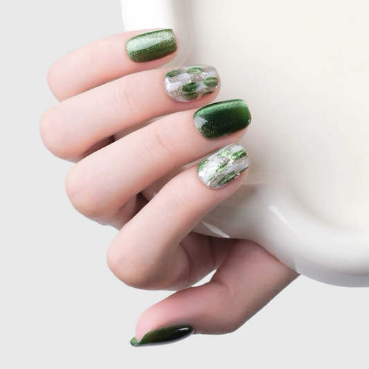 Hand with green nail polish holding a white mug on a light background