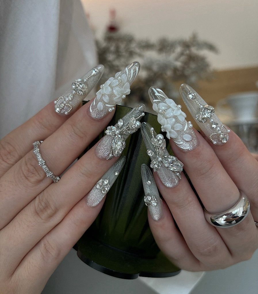 Close-up of hands with decorative nail art holding a green bottle.