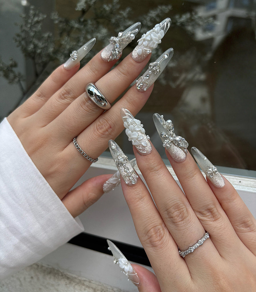 Close-up of hands with decorative nails and rings against a blurred background