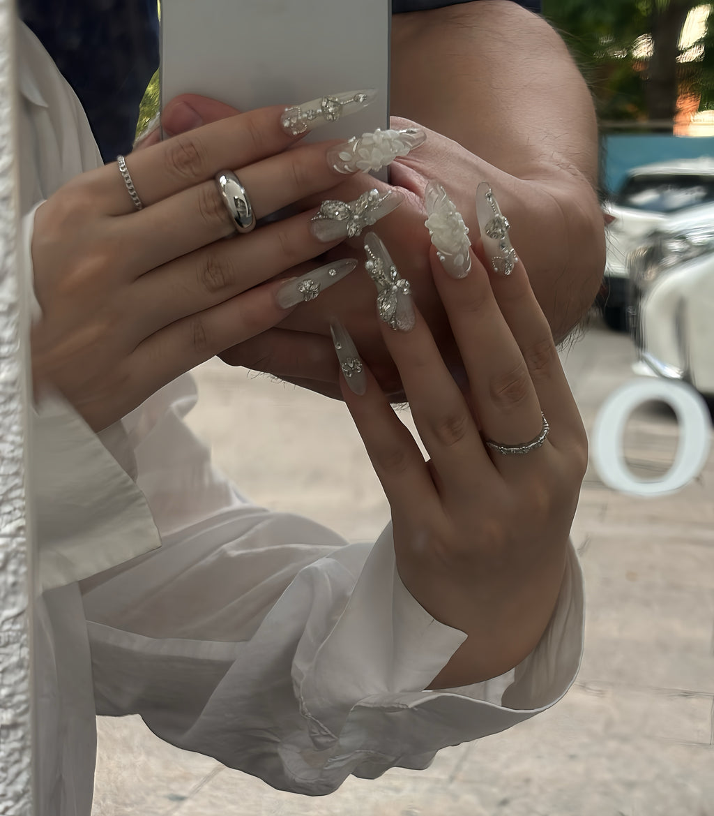 Close-up of hands with decorative nails and rings, blurred background