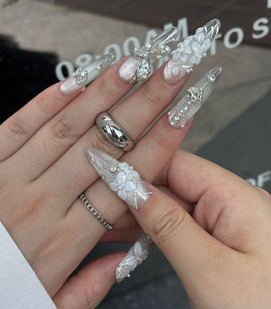 Hand with decorative nail art and rings on a blurred background