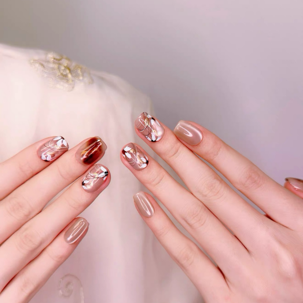 Close-up of hands with decorative nail art on a neutral background