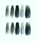 Set of green and black nail extensions on a white background