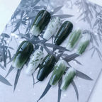 Set of green and white nail designs on a leaf-patterned surface