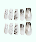 Set of press-on nails with black and white marbled design on a white background