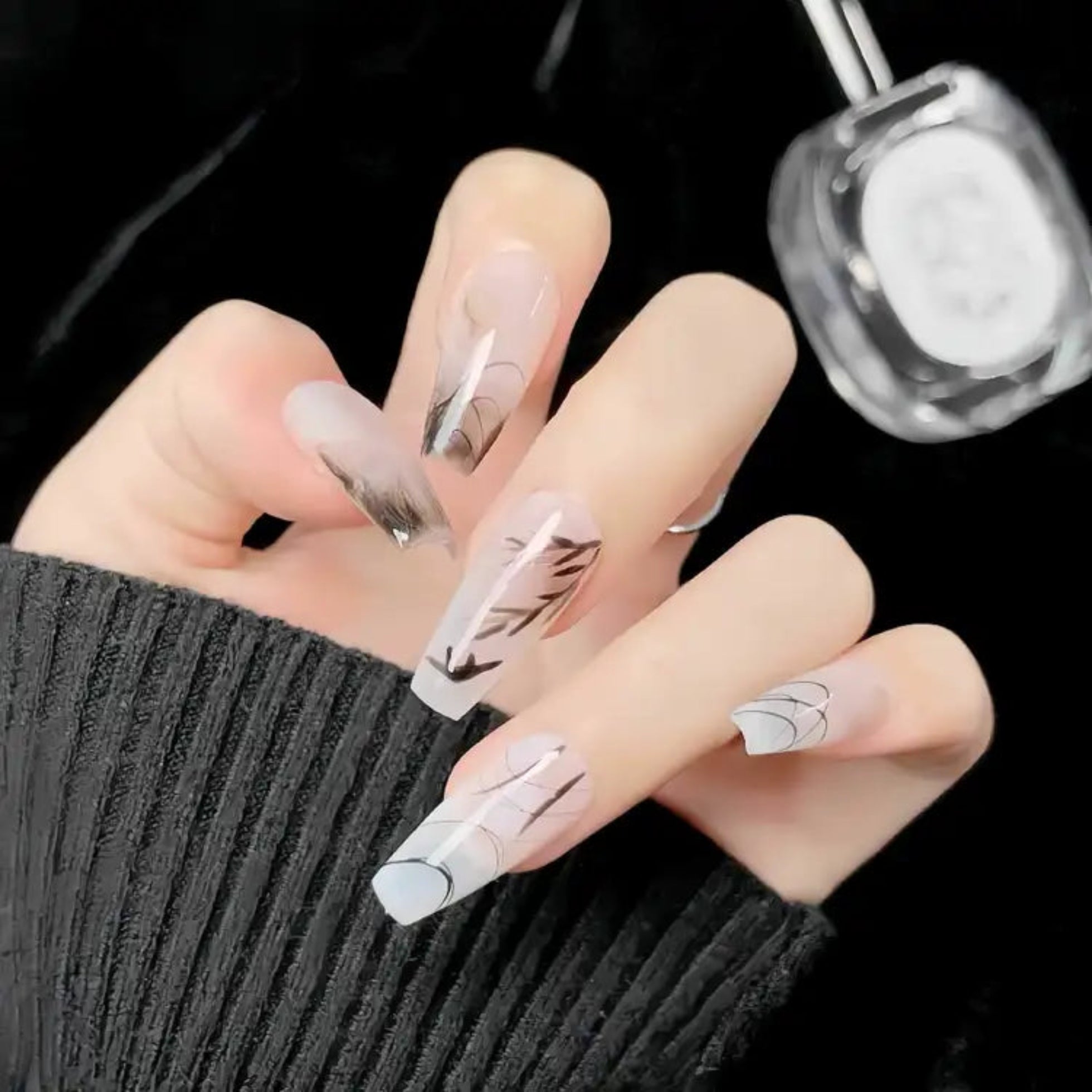 Hand with decorative nails and a bottle of nail polish on a dark background