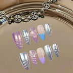 Set of decorative nails with pastel and metallic colors on a reflective surface.