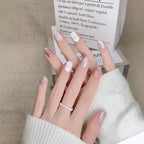 Close-up of a hand with stylish nail art holding a box.