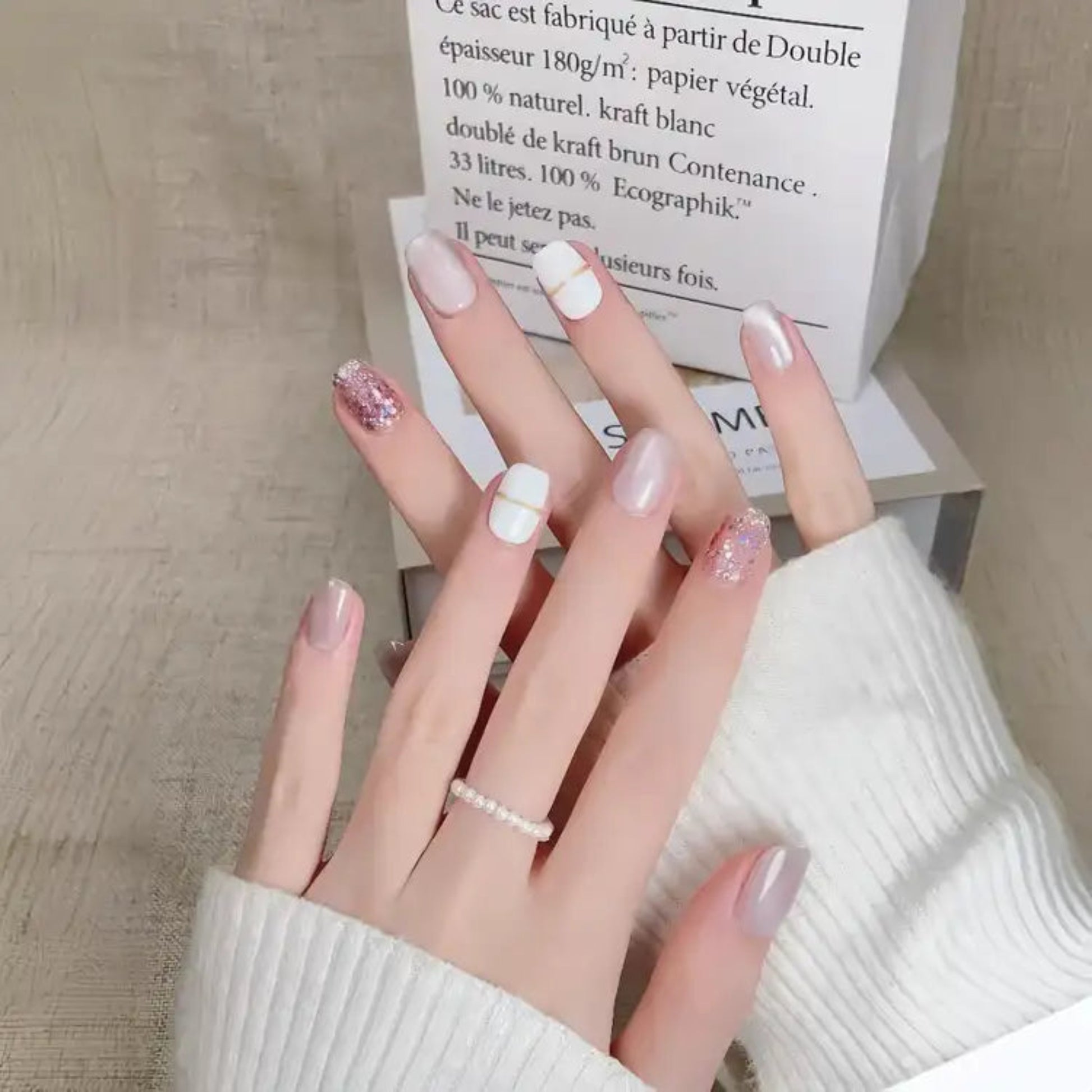 Close-up of a hand with stylish nail art holding a box.