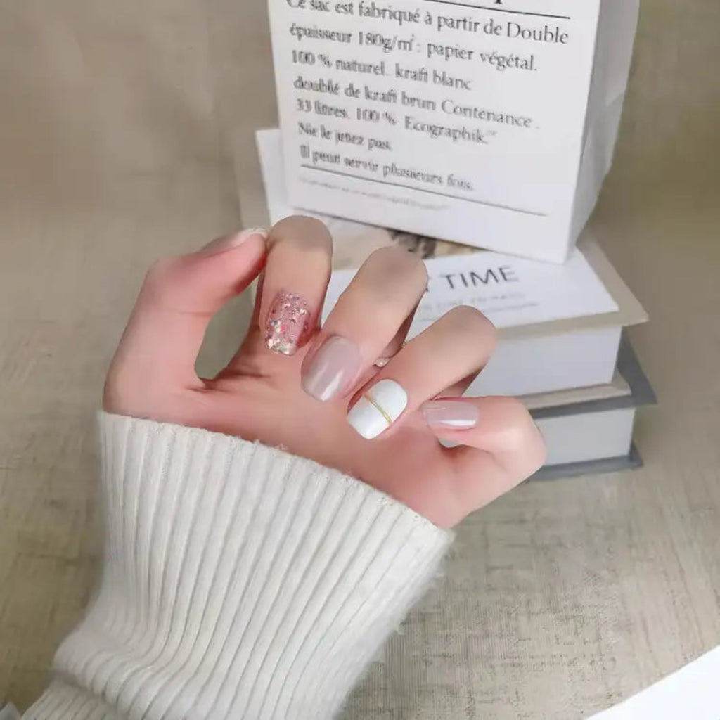 Hand with stylish nail design holding a magazine on a textured surface