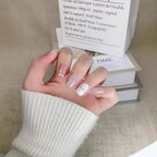 Hand with stylish nail design holding a magazine on a textured surface